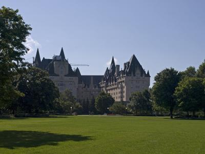 A large, castle-like hotel with multiple steeples and turrets is visible in the background behind a wide, green lawn and trees.