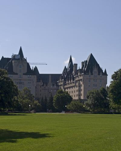 A large, castle-like hotel with multiple steeples and turrets is visible in the background behind a wide, green lawn and trees.