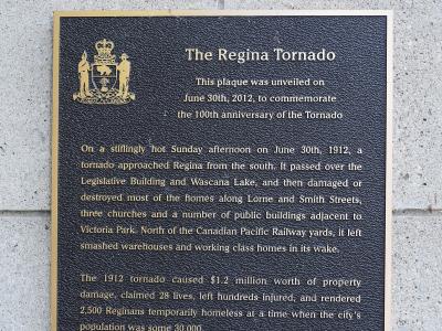 A close-up photograph of a commemorative plaque mounted on a concrete block wall, titled "The Regina Tornado" and detailing the events of June 30, 1912.