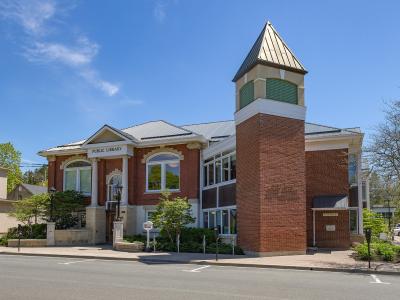 A red brick and stone building with a prominent corner tower, featuring signage reading "PUBLIC LIBRARY" above the main entrance and "PORT HOPE PUBLIC LIBRARY" in raised lettering on the brick tower.