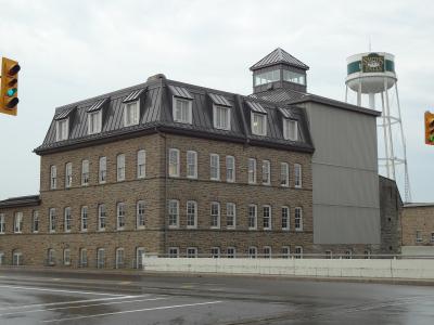 A large stone industrial building with a mansard roof and a water tower in the background displaying the text "SMITHS FALLS".