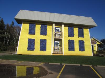 A large, yellow, two-story building with blue shutters and a grey roof, featuring a sign on the right side that reads "Cavendish Adventure Zone".