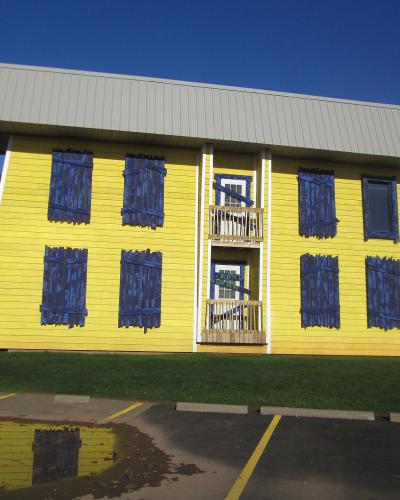 A large, yellow, two-story building with blue shutters and a grey roof, featuring a sign on the right side that reads "Cavendish Adventure Zone".