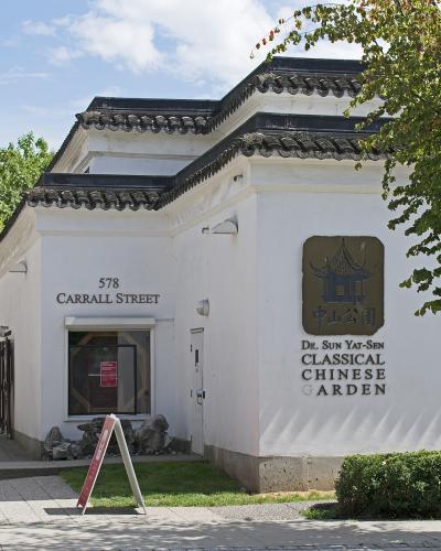 A white building with traditional Chinese architectural features, displaying a sign that reads "Dr. Sun Yat-Sen Classical Chinese Garden" and the address "578 Carrall Street".