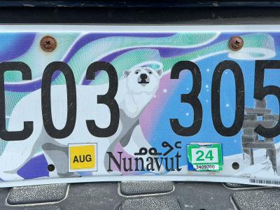 A close-up photograph of a vehicle license plate featuring a polar bear, an inuksuk, and the word "Nunavut" printed at the bottom center.