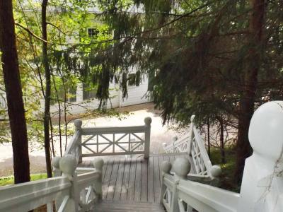 A view looking down a wooden staircase with white railings towards a white building partially obscured by trees.