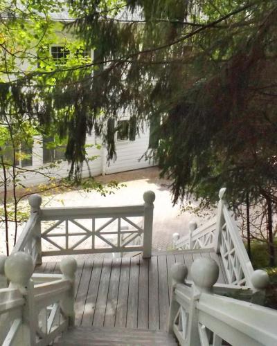 A view looking down a wooden staircase with white railings towards a white building partially obscured by trees.
