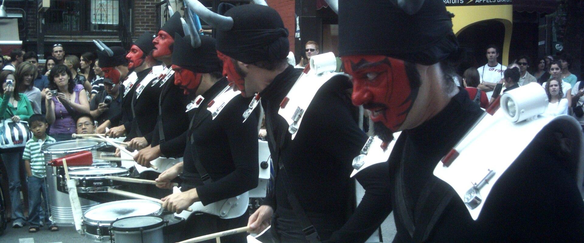 Costumed drummers in a Just for Laughs festival parade in Montreal