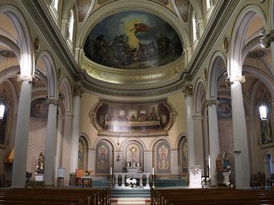 The interior of a historic church featuring a barrel-vaulted ceiling with a large fresco, a mural of the Last Supper above the altar, and a Latin inscription reading "SALE SALIS QUOD ME PERSEQUERIS".