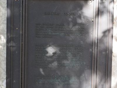A close-up photograph of a bronze commemorative plaque mounted on a stone wall, titled "SPEAKERS' CORNER" and dedicated to the people of Saskatchewan.