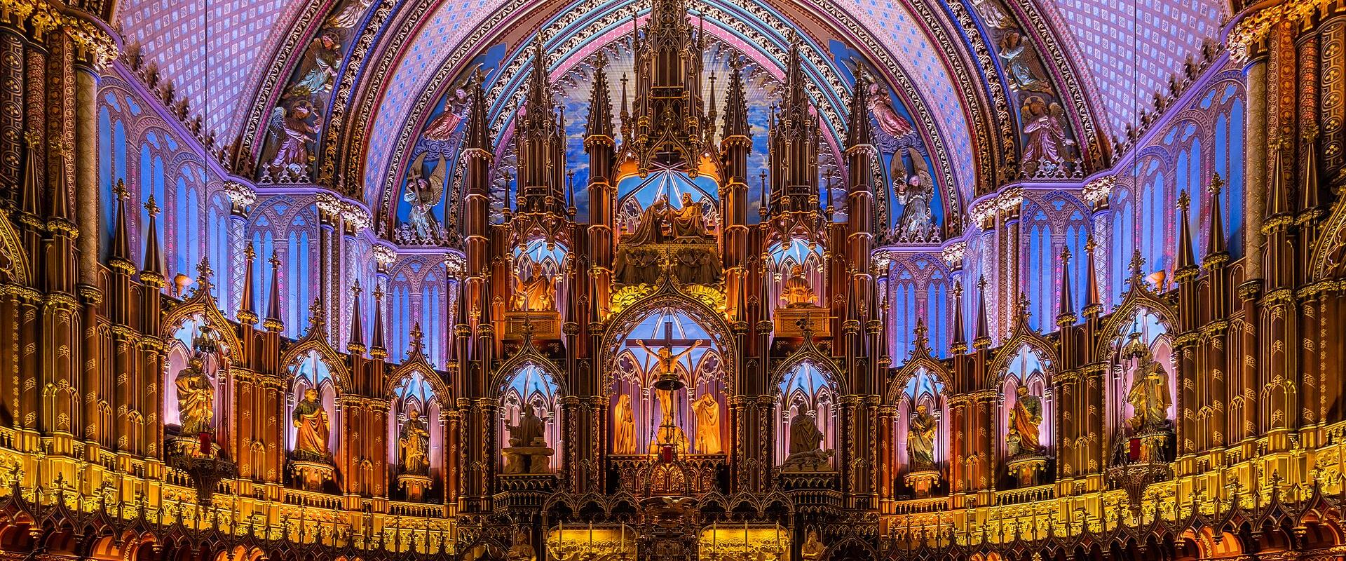 The image shows the ornate interior of a Gothic Revival basilica, featuring a highly decorated golden altar, a painted vaulted ceiling with blue and gold patterns, and rows of pews.